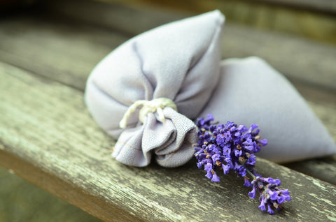 Duftsäckchen neben Lavendelblüte auf Holztisch