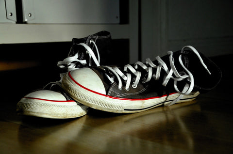 Getragene schwarz-weiße Converse-Sneaker auf Fußboden