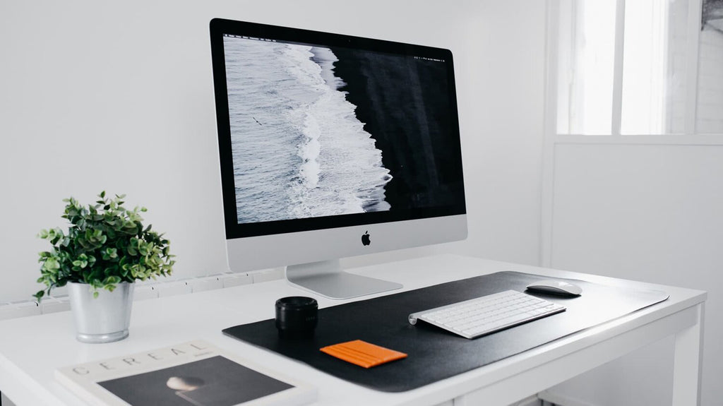 Clean white desk setup with Apple iMac and plant decor in a Singapore workspace.