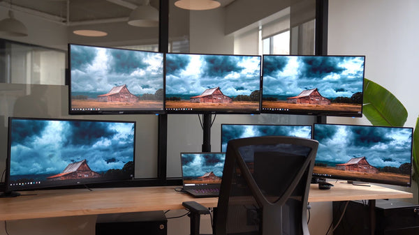 Multiple monitor setup with ergonomic monitor arms for an efficient trading desk workspace in Singapore.