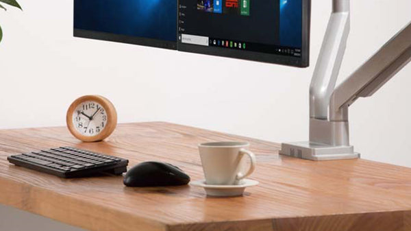 Sleek dual monitor setup with ergonomic monitor arms and a clock on the desk, Singapore.