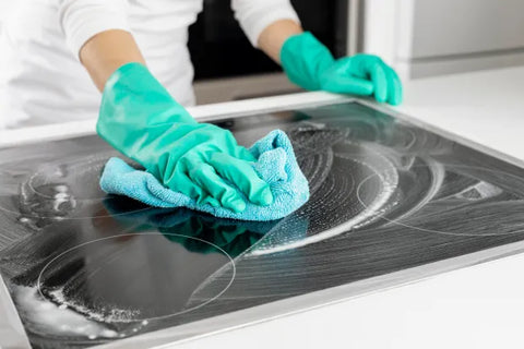 A woman cleaning an electric kitchen hob