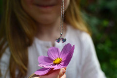 Girl holding a flower with a dangling silver birds necklace