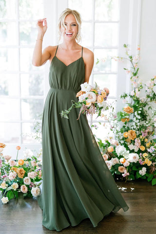 A bridesmaid wears an olive green dress in a wedding photo with a cream and eucalyptus bouquet