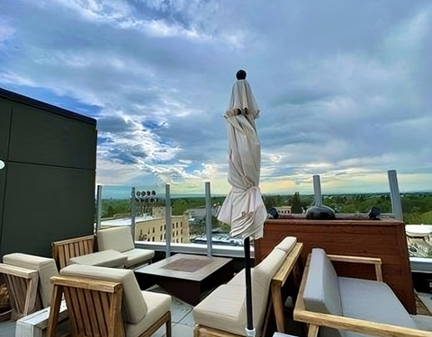 A rooftop patio featuring chairs and umbrellas, providing a relaxing outdoor space with a scenic view.