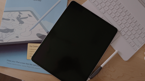 An iPad, Apple Pencil, Magic Keyboard, and Paperlike screen protector are sitting on a desk