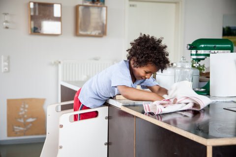 Kind steht auf Montessori Lernturm in der Küche