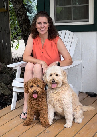 Rebecca sitting in white chair on porch with two mini Goldendoodle dogs