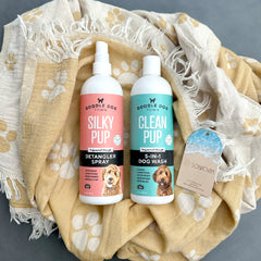 Silky Pup Detangler Spray and Clean Pup Dog Wash Bottles lying on paw print Solwoven Towel
