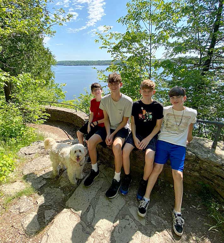 4 boys sitting on rock ledge with dog in front of Lake Michigan in Door County Wi