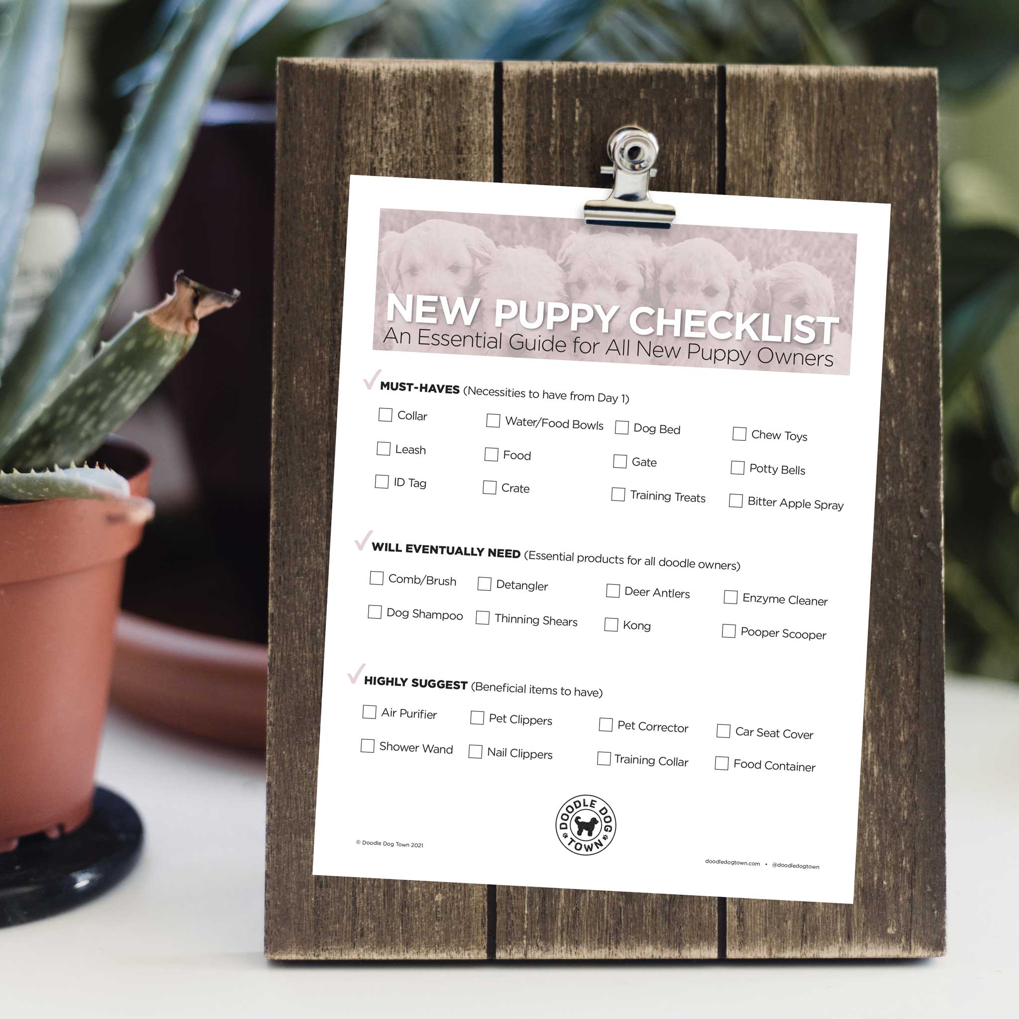 New Puppy Checklist sheet on wooden plank clipboard surrounded by plants