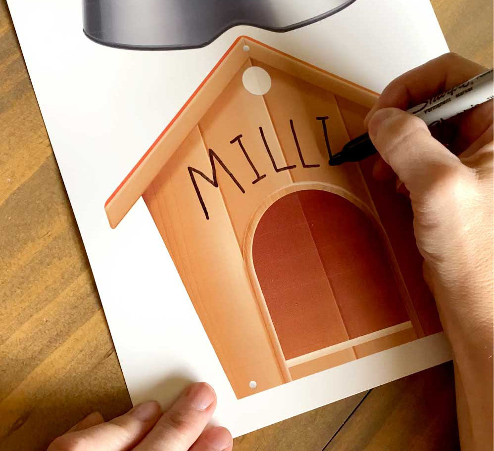 woman's hand writing the name Millie on dog house printable