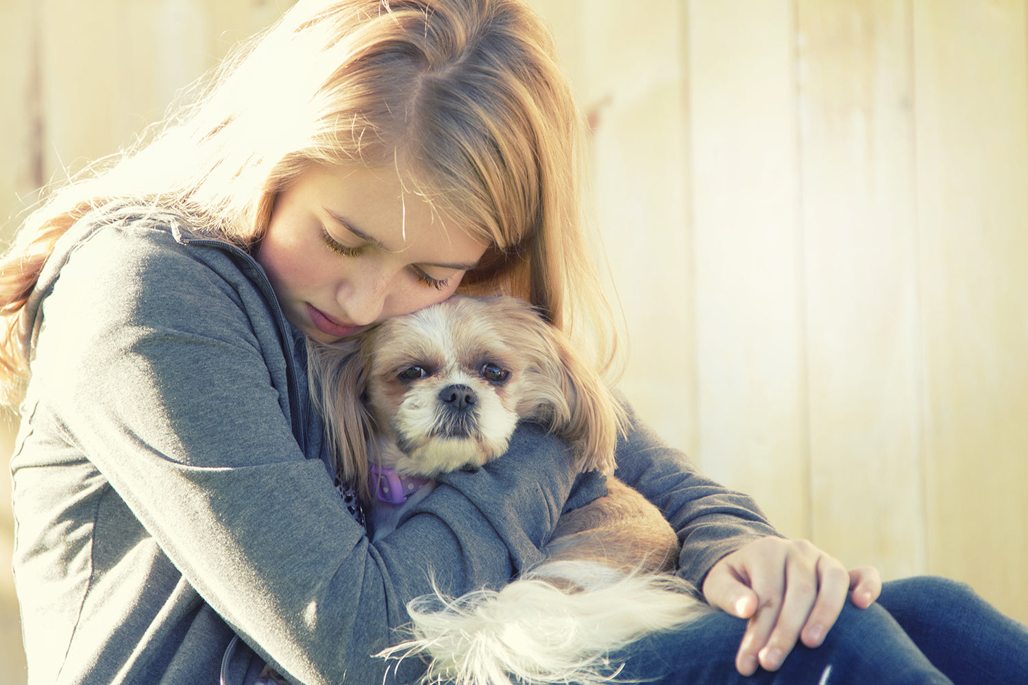 young lady with blond hair holding scared dog close to her face