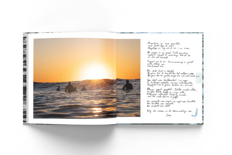 Mockup of the memorial book with the photograph of a sunset with surfers in the water.