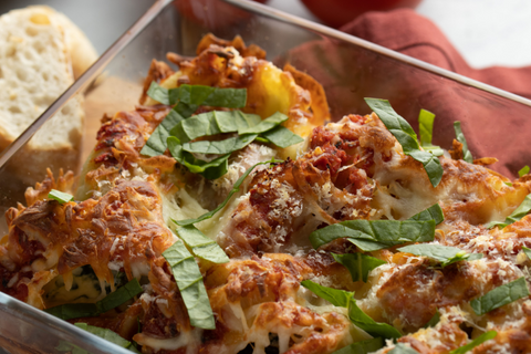 Garnish lumaconi pasta bake casserole with strips of chopped basil and accompany with bread and meats
