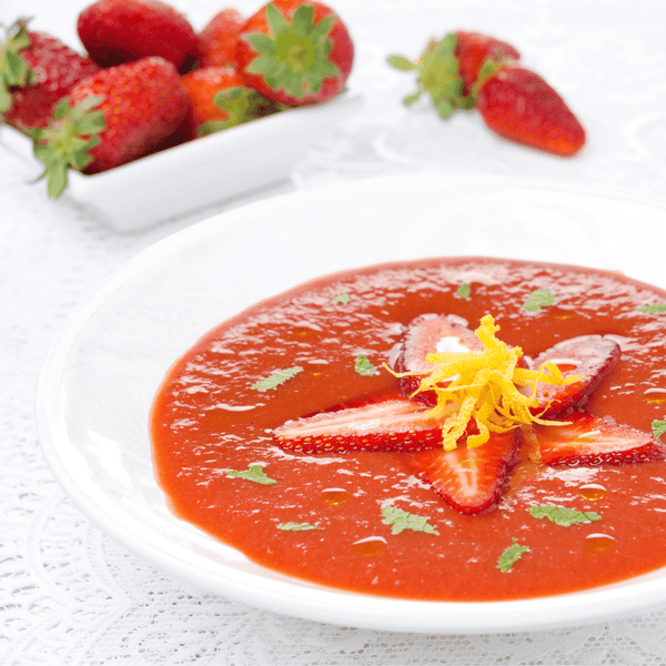 Strawberry gazpacho with decorated cheese garments and parsley.