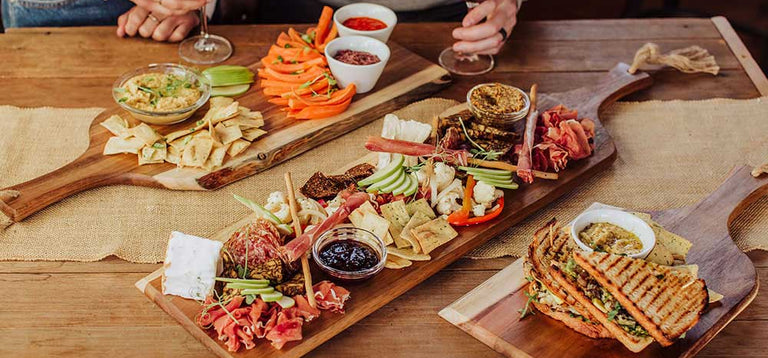Three Toscana charcuterie boards loaded with delicious snacks