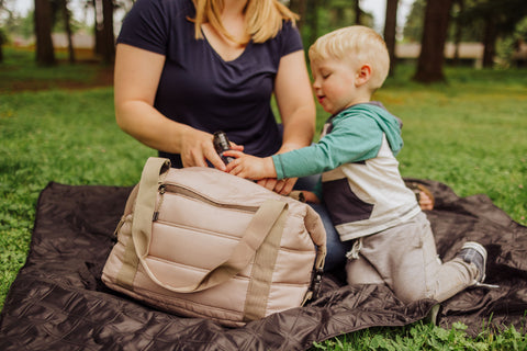 woman and child opening machine washable cooler tote while sitting on a picnic blanket