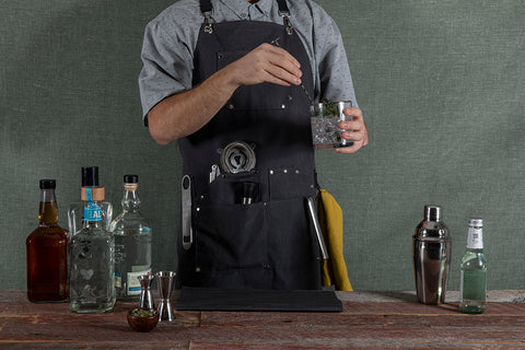 man mixing a cocktail wearing a mixology apron
