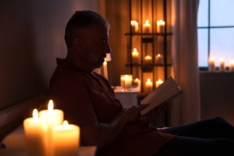 man reading book in candle light