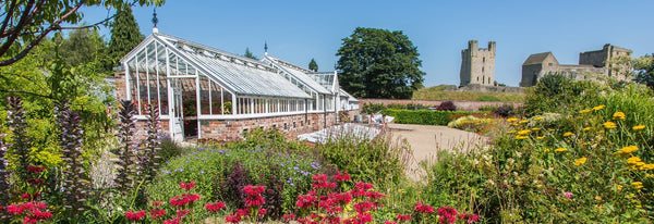 A picturesque accessible garden with a greenhouse and vibrant flowers at Helmsley Walled Garden in North Yorkshire.