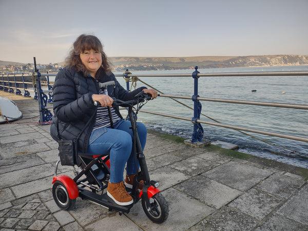 A woman happily riding her folding mobility scooter.