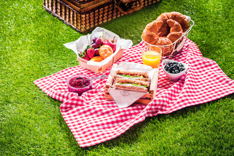 Picnic basket with delicious food spread out on the grass.