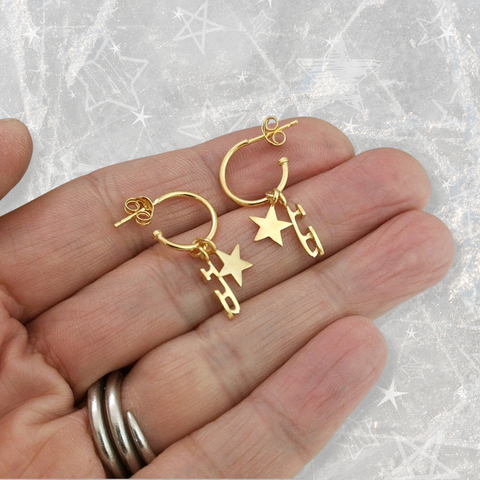 A hand holding some gold stud hoop earrings