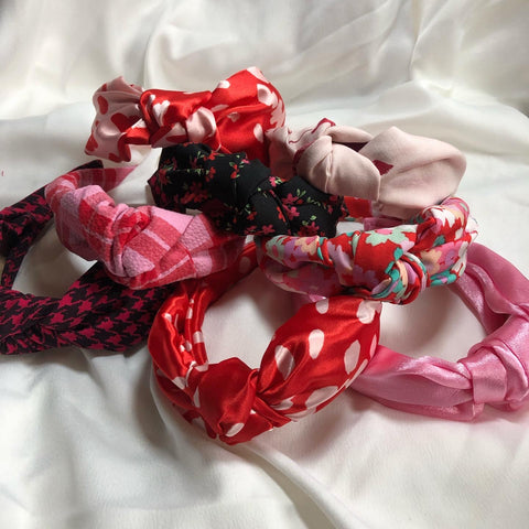 8 classic knot headbands in various colours, patterns and textures. The colour palette is pink and red.