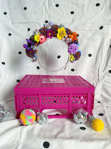 A bright and multicoloured faux flower crown on a stand 