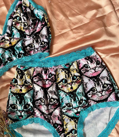 Flat lay of a soft wireless bra and matching pants featuring an all over print of a kitten in yellow, blue and pink