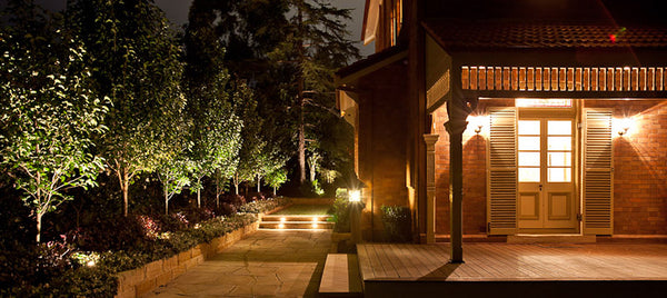 Cozy porch at night lit up by warm white landscape lighting