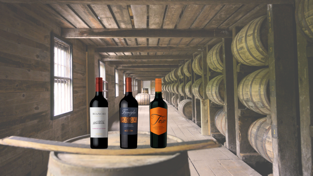 Three Argentinian wines on a wine barrel with a barrel room in the background