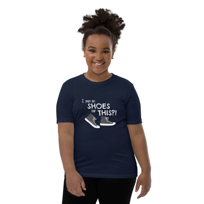 Model wearing Navy youth t-shirt with graphic of black and white canvas "chuck" sneakers and text: "I put on SHOES for THIS?!"