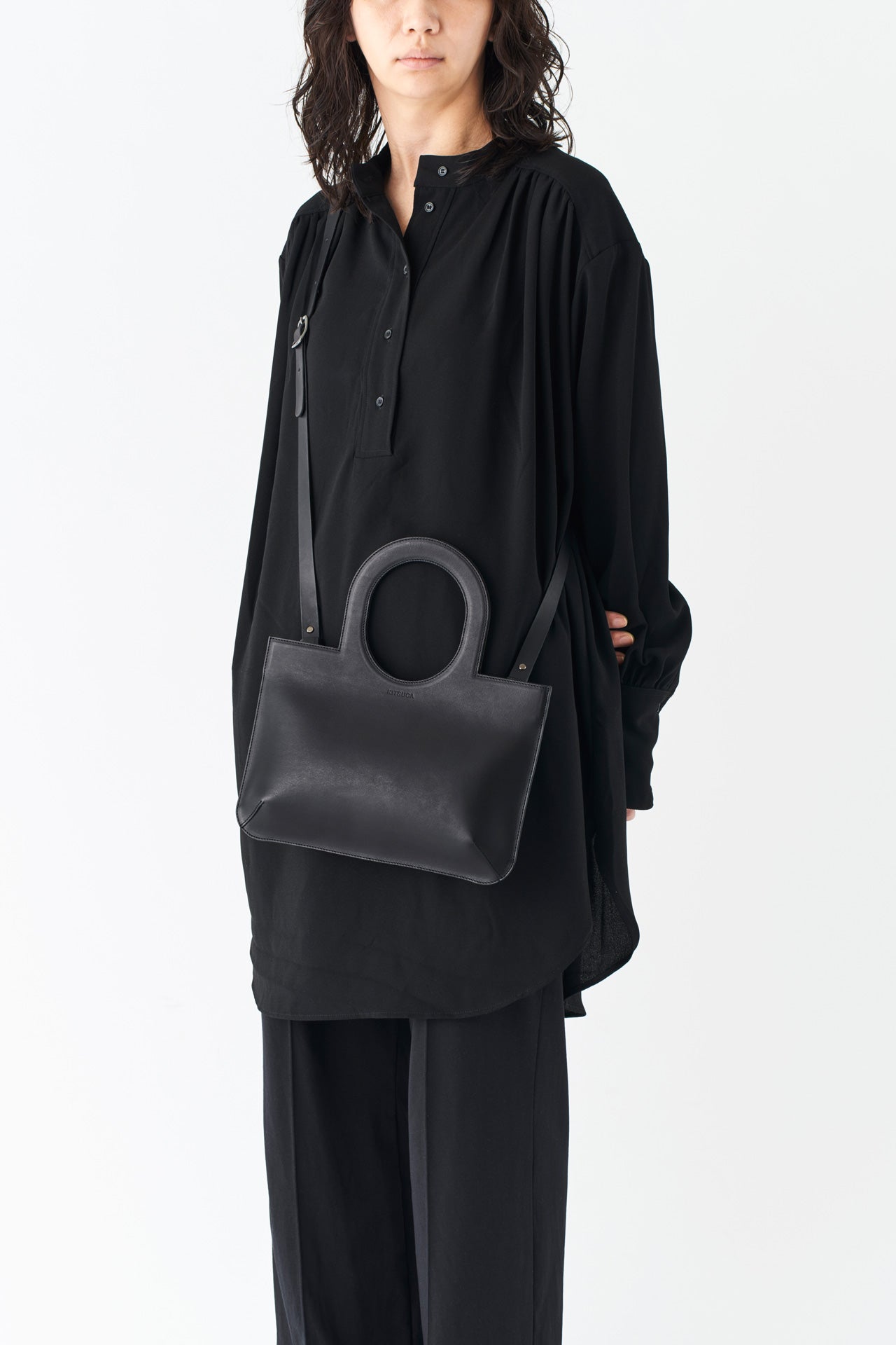 シンプルなレザーのショルダーハンドバッグとモードスタイルの女性