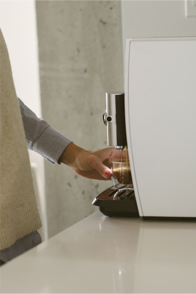 A woman making a coffee with an automatic coffee machine