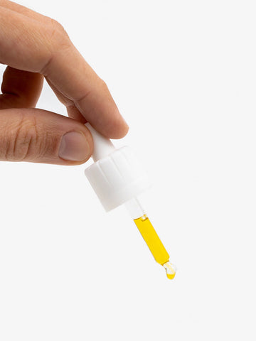 A man's hand holds a pipette with CBD oil (10%).