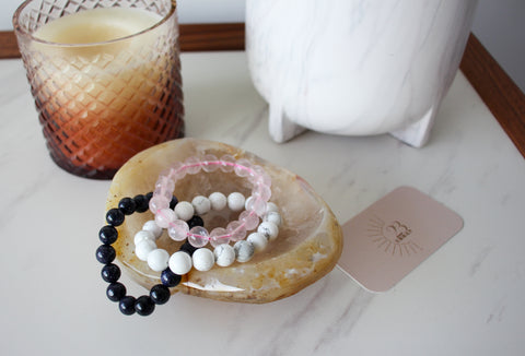 Three crystal bracelets inside a brown agate bowl on a bedside table 