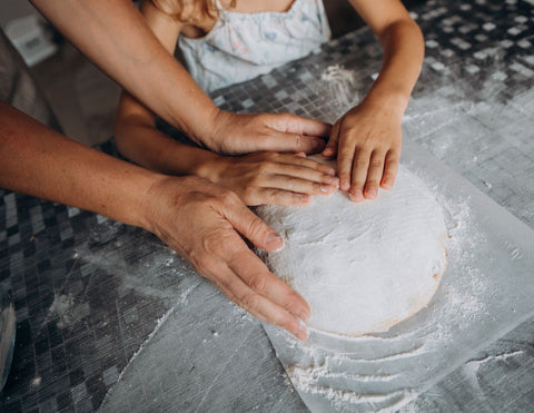 A mother teaching a child to make bread