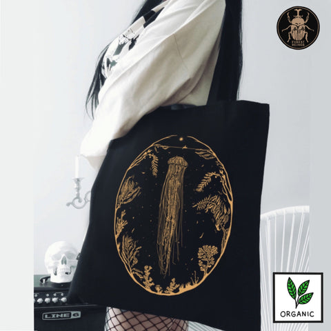 A girl holding a goth tote bag with golden jellyfish design on it.
