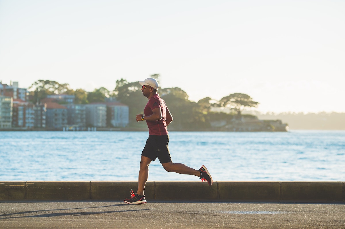 Man running along sidewalk by water