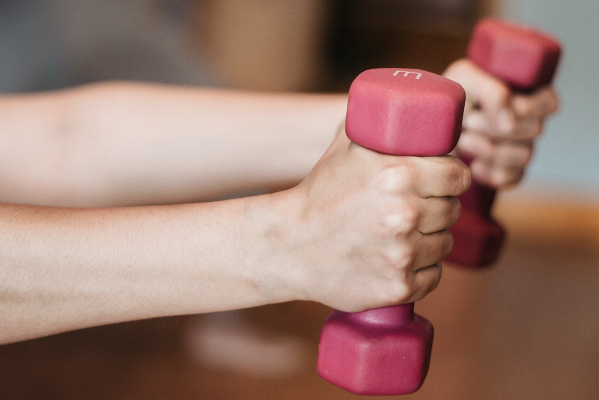 Two hands lifting pink weights