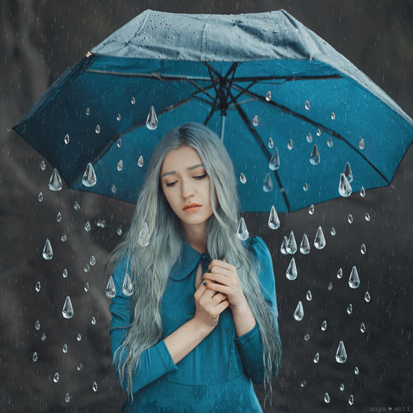 an Anya Anti photograph of a young woman holding an umbrella with oversized raindrops falling, all on a dark background