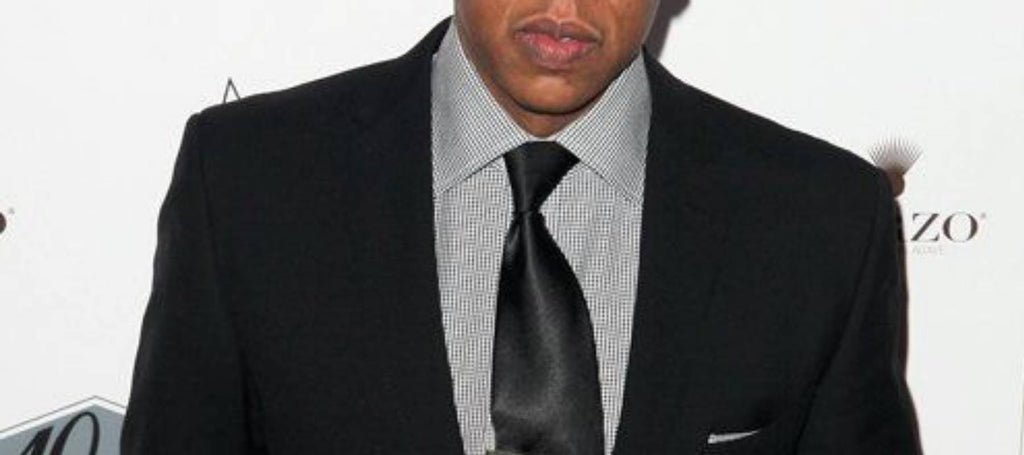 Ein Mann mit einem schwarzen Anzug, einer schwarzen Krawatte und einem grauen Hemd