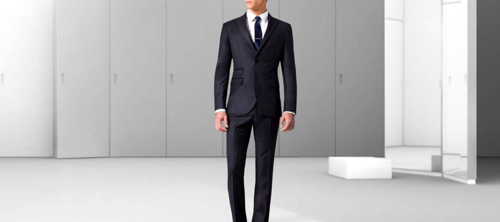 Ein Mann in der Mitte eines weißen Raumes mit einem schwarzen, taillierten Anzug