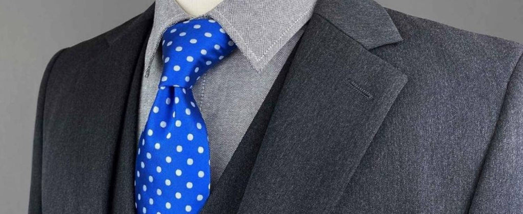 Corbata de lunares azules con traje de tres piezas gris y camisa gris