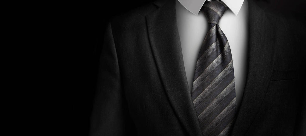 Mann, der einen schwarzen Anzug und eine graue Krawatte trägt