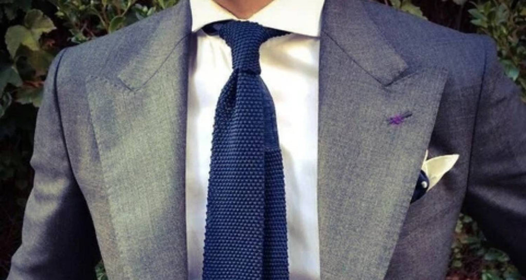Corbata de punto azul en hombre, traje gris y camisa blanca