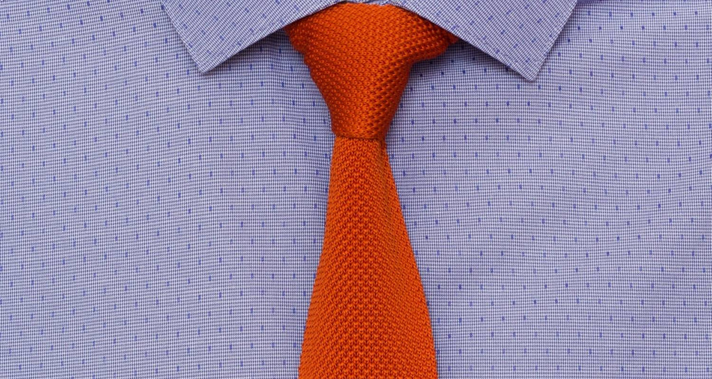 Corbata de punto naranja sobre camisa 