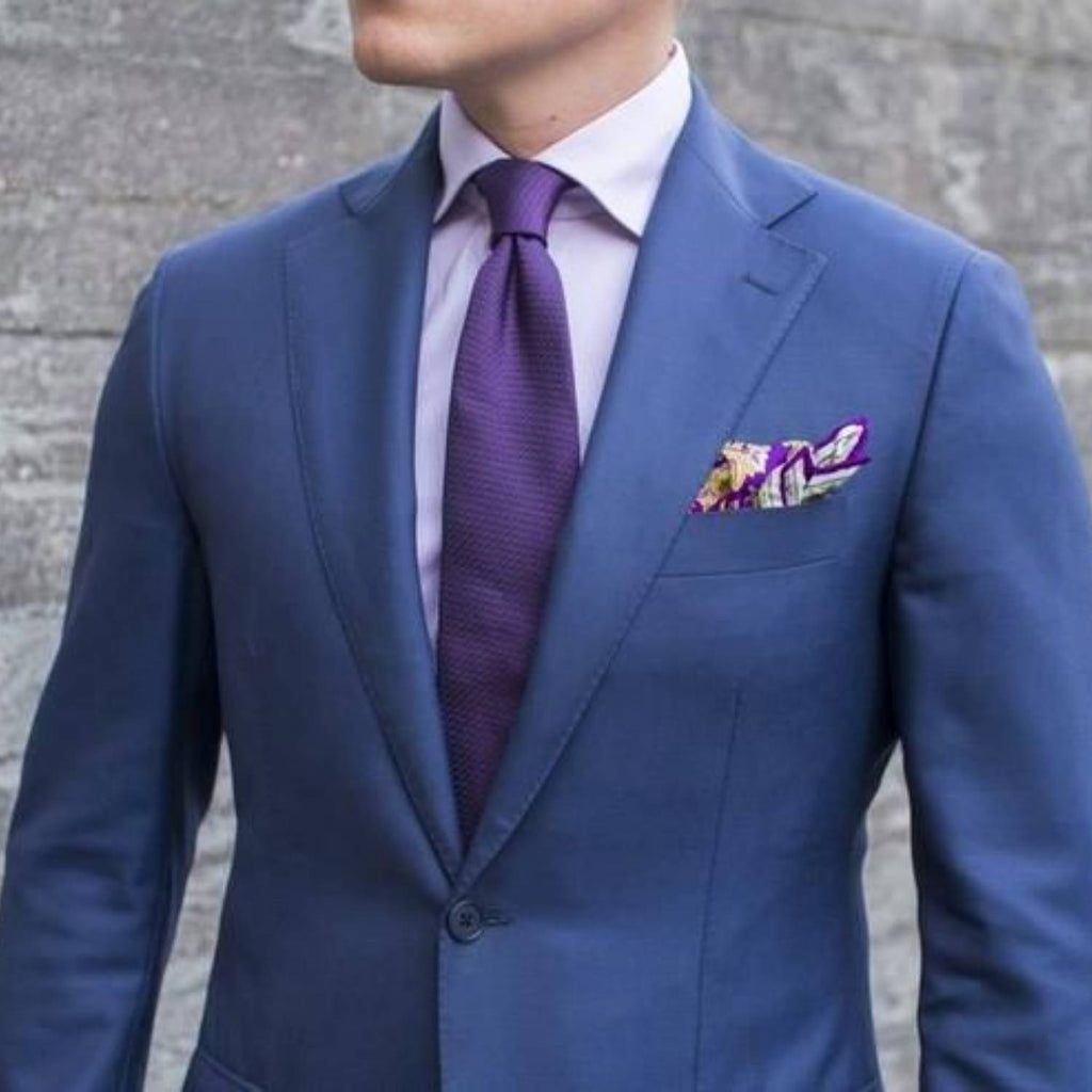 Hombre con traje azul, camisa rosa y corbata morada